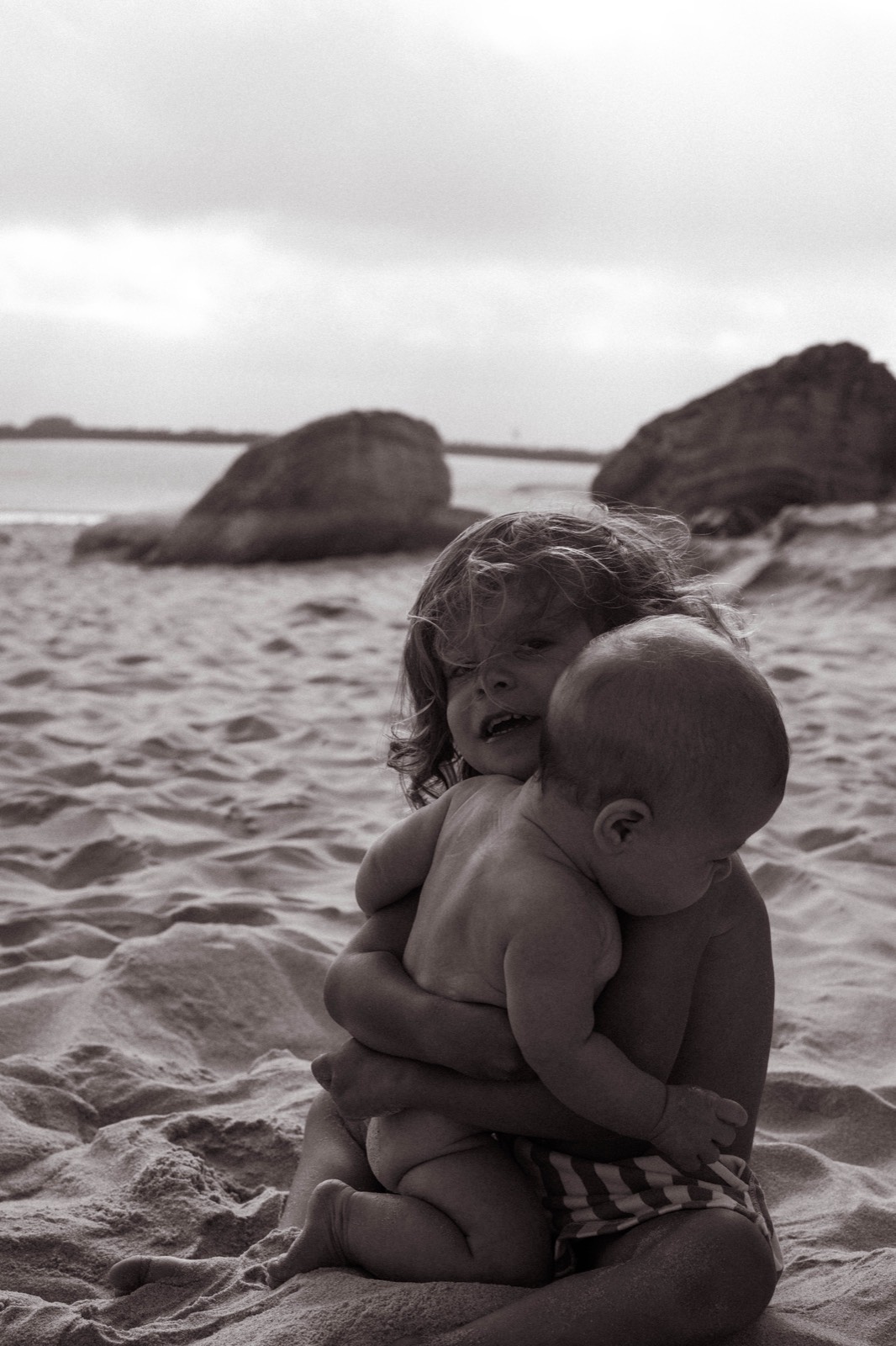 Two young siblings embracing on the sand