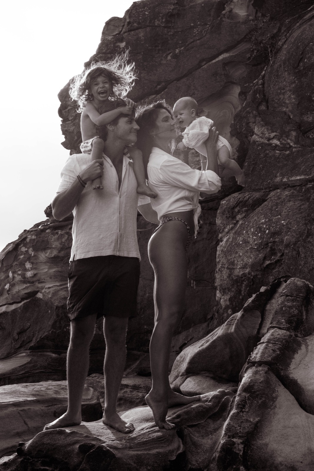 Family standing together among coastal rocks