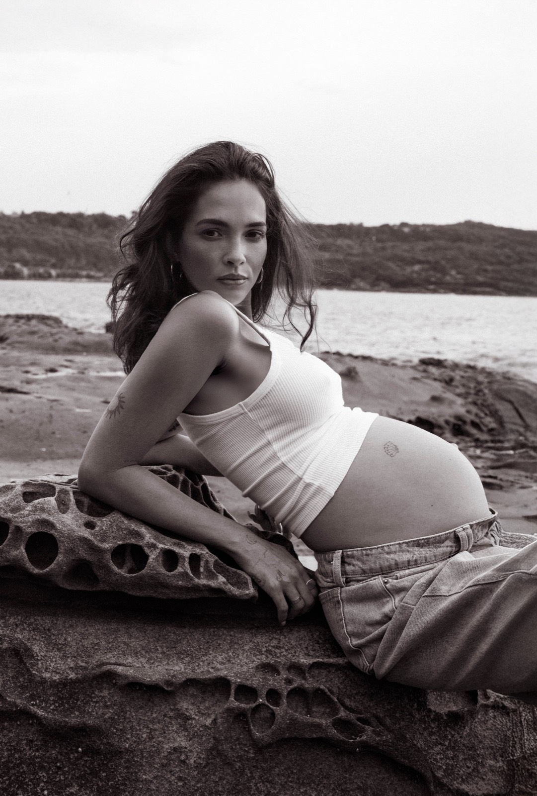 Relaxed black and white maternity portrait reclining on coastal rock