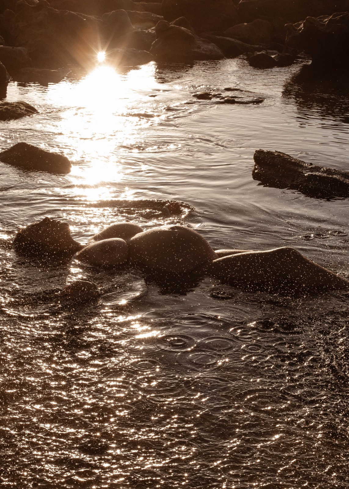 Sculptural maternity silhouette floating in reflective water