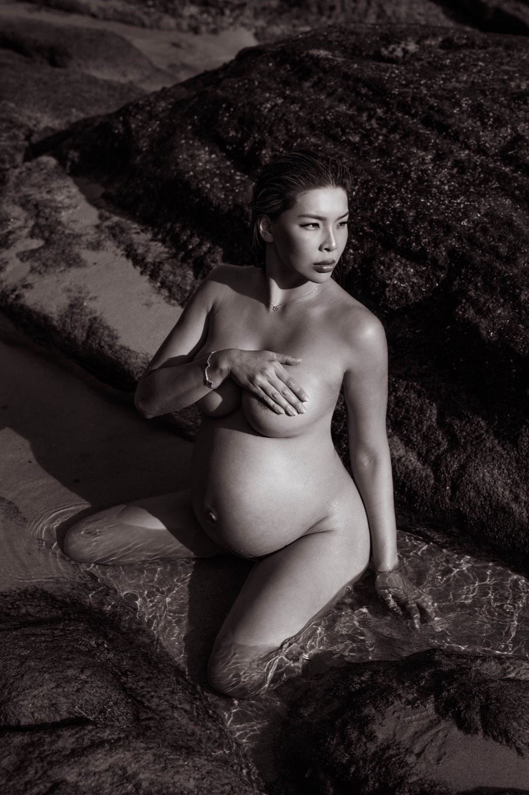Black and white maternity portrait seated in shallow water