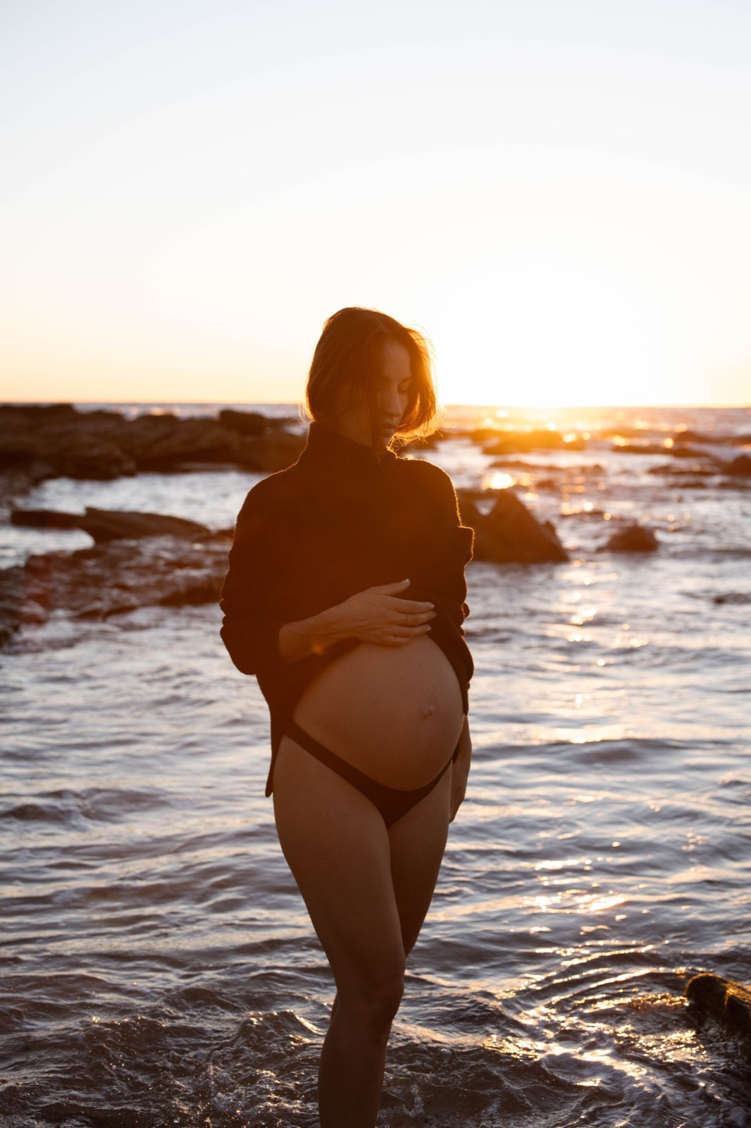 Quiet maternity portrait silhouetted against the setting sun