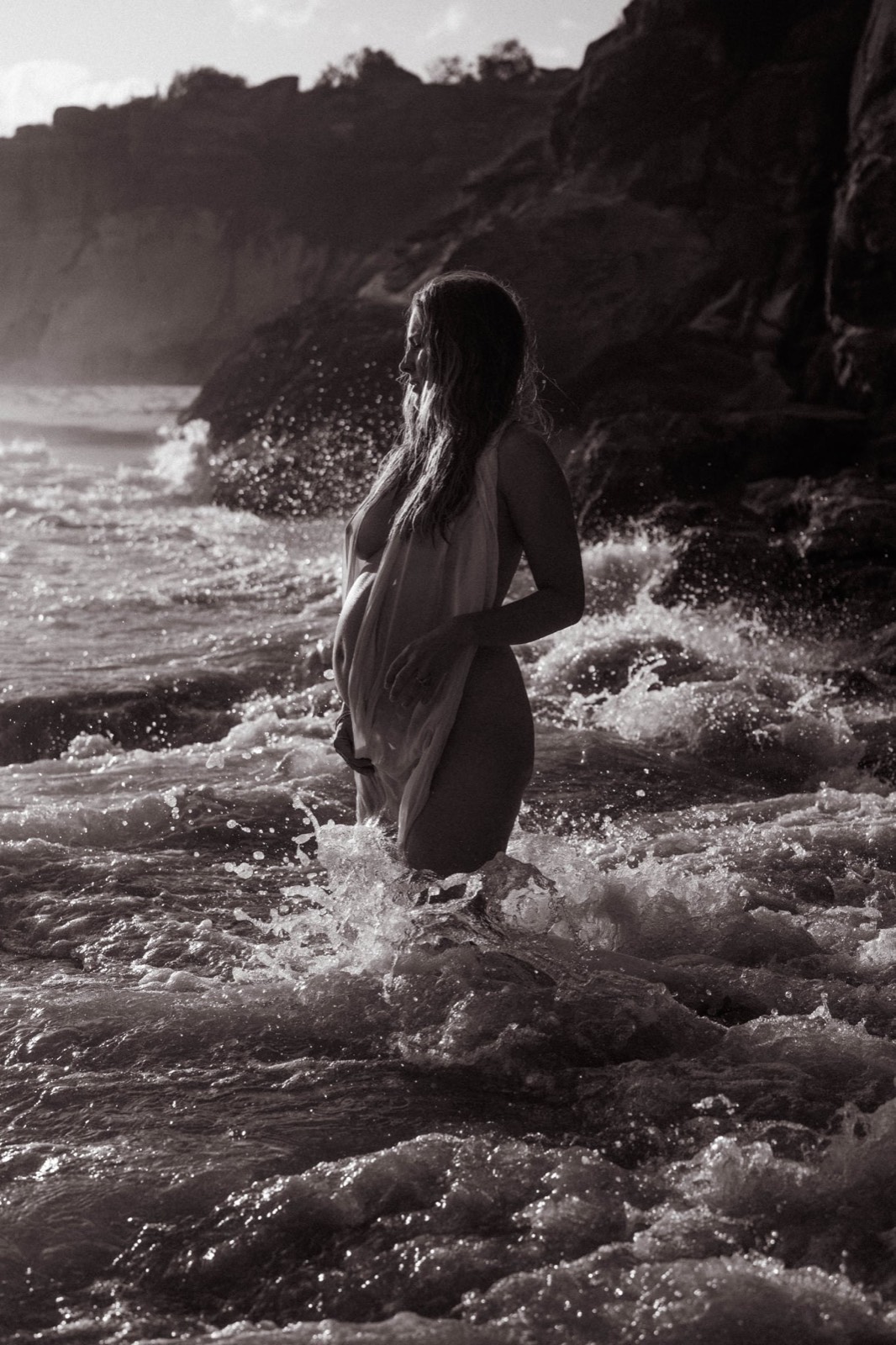 Black and white maternity portrait standing in the ocean
