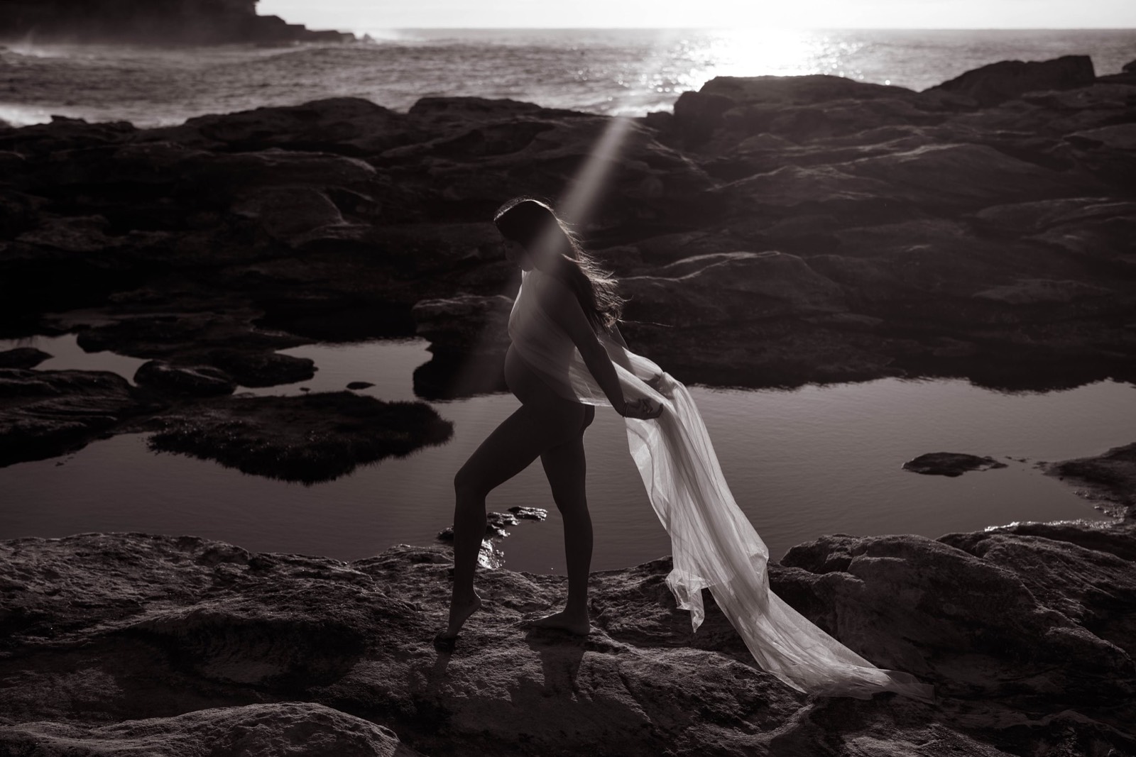 Black and white maternity silhouette moving through a shaft of light