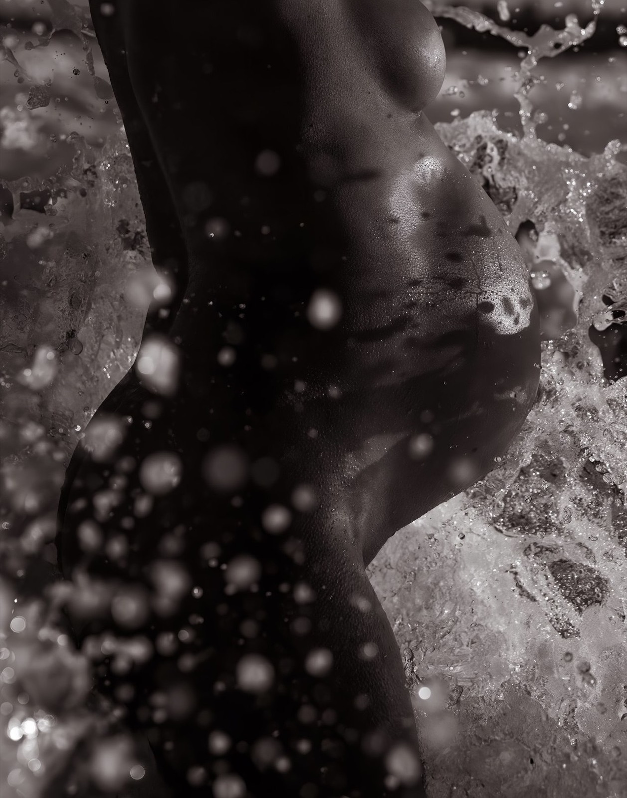 Abstract black and white maternity portrait surrounded by breaking water