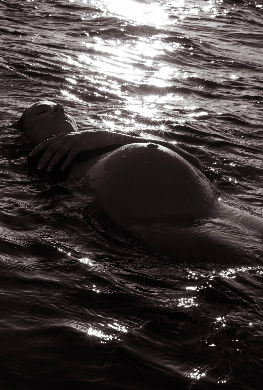 Pregnant figure floating peacefully in sunlit water