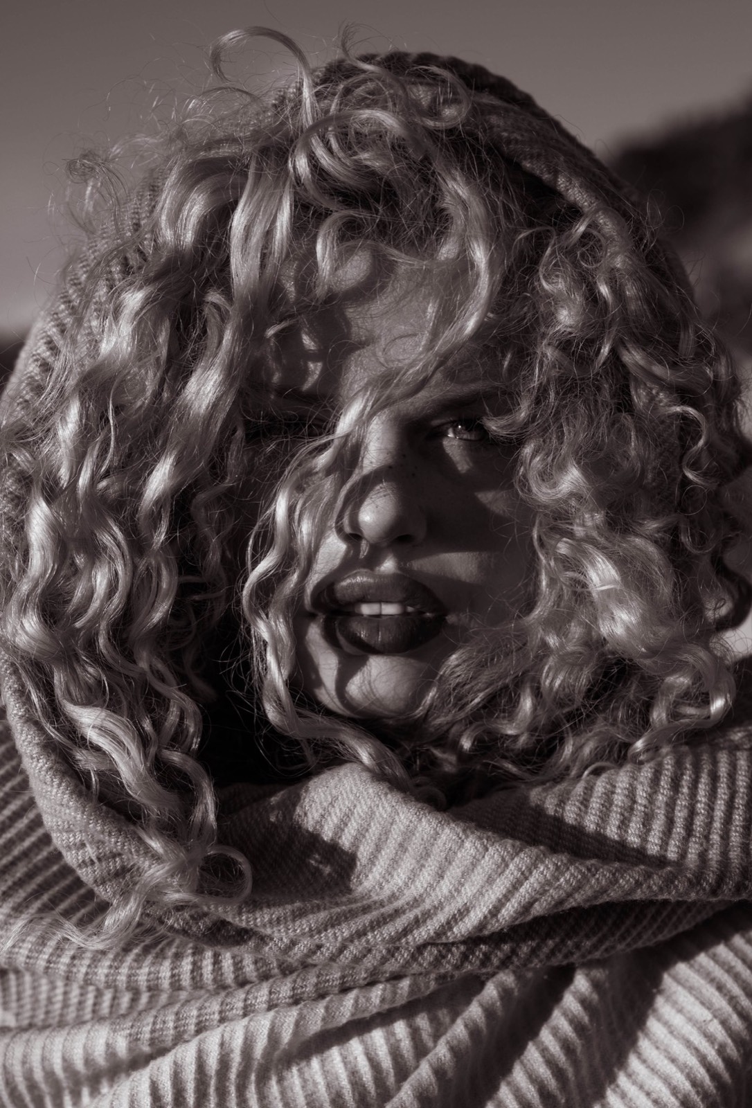 Close black and white editorial portrait framed by sculptural curls